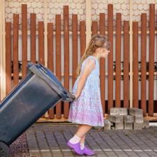 young girl taking out trash at home